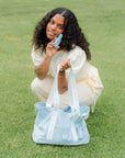 Woman holding a light blue Bloomeffects tote bag on grass