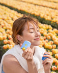 Girl in tulip fields applying Bloomeffects Tulip Dew Shield & Glow