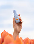 Vitamin C Facial Oil in hand in a tulip field