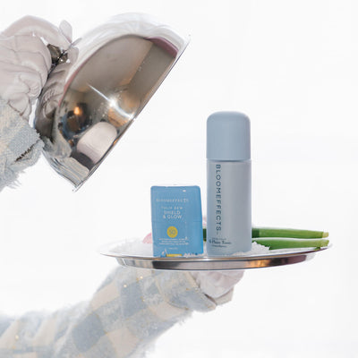 Bloomeffects skincare products on a tray held by a gloved hand.