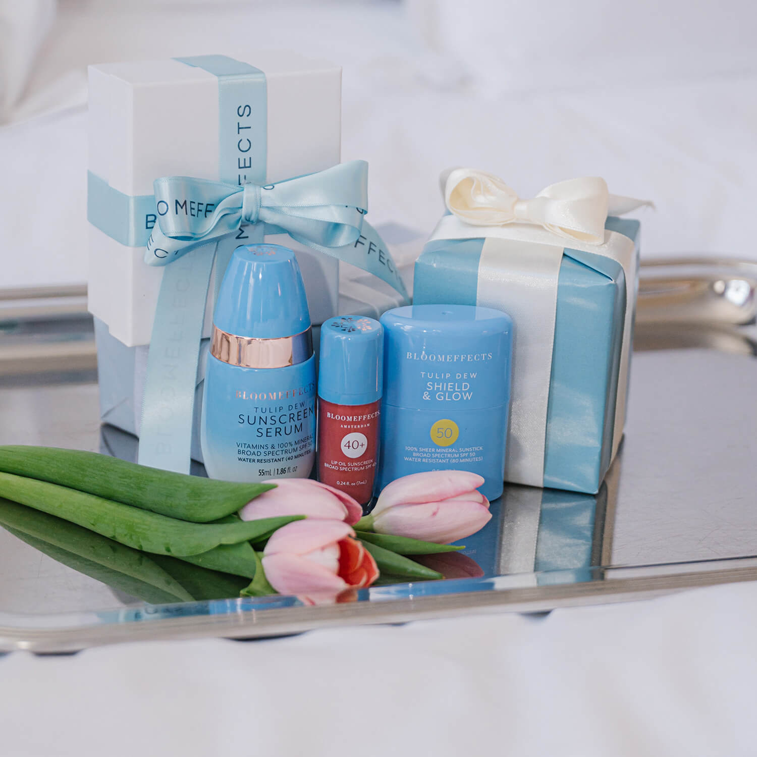 Cosmetic products with decorative boxes and flowers on a reflective surface