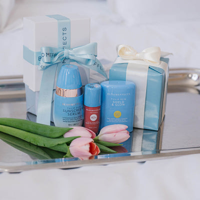 Cosmetic products with decorative boxes and flowers on a reflective surface