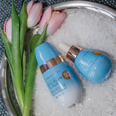 Two skincare products on a textured surface with tulips in the background