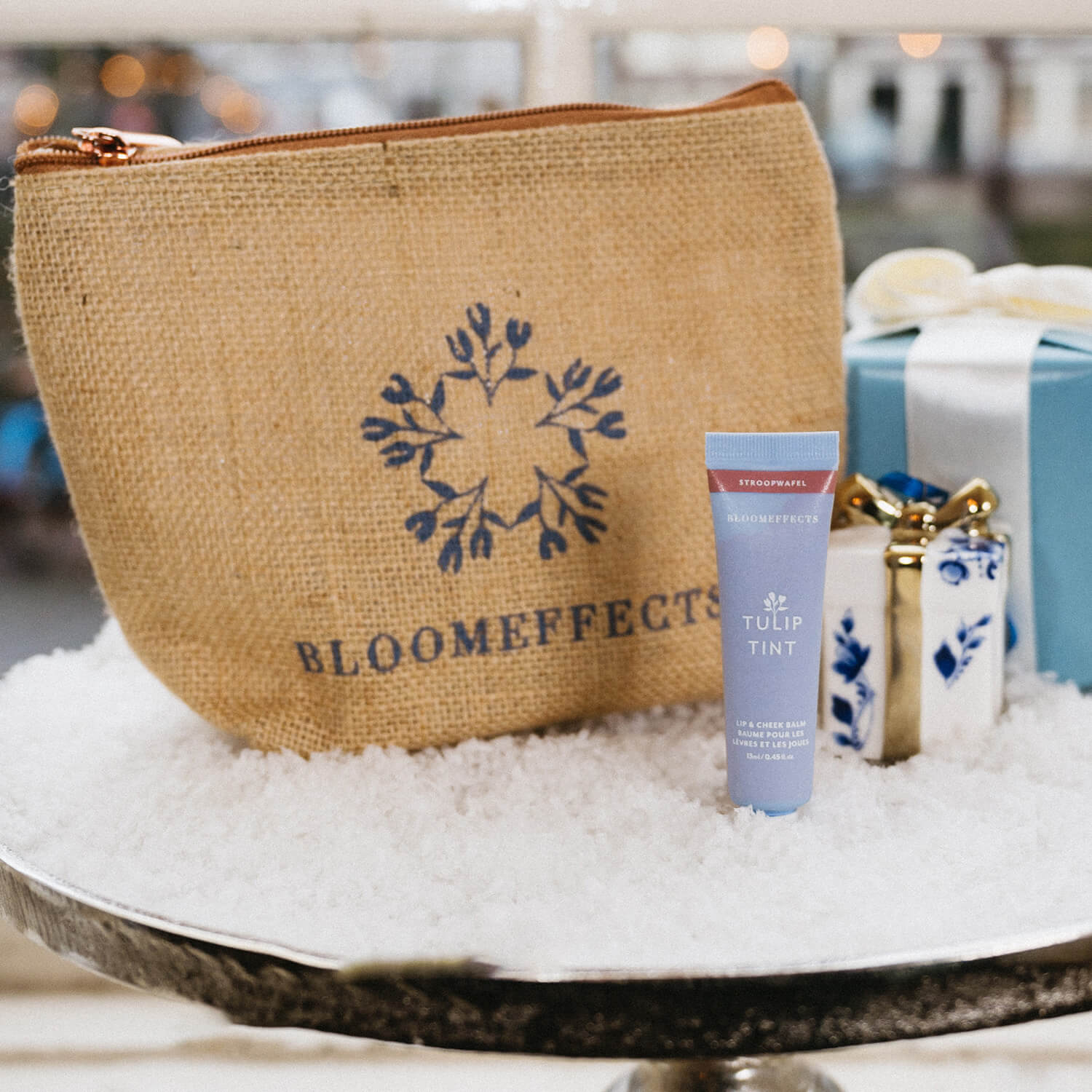 Bloom Effects cosmetic bag with a tube of Tulip Tint on a decorative surface.