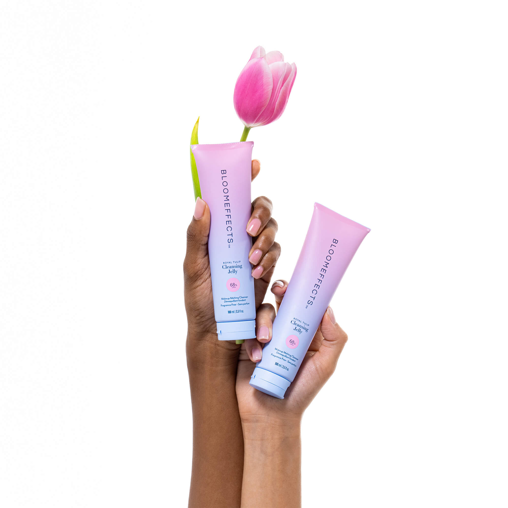 Two tubes of Bloomeffects Cleansing Jelly held by a hand with a pink tulip in the background.
