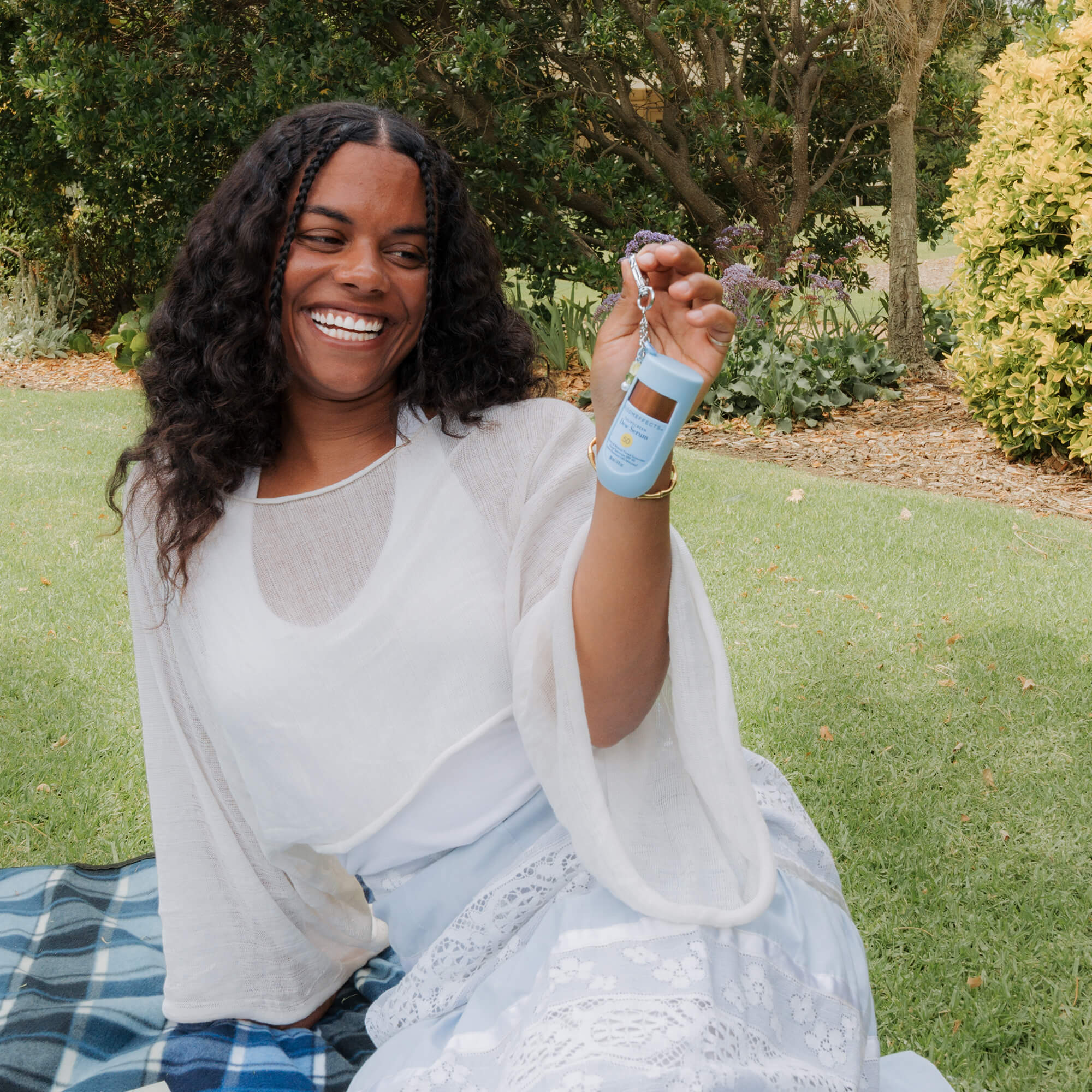 Woman sitting on a blanket outdoors, holding a Bloomeffects product