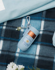 Keychain with Bloomeffects skincare product on a blue plaid fabric background