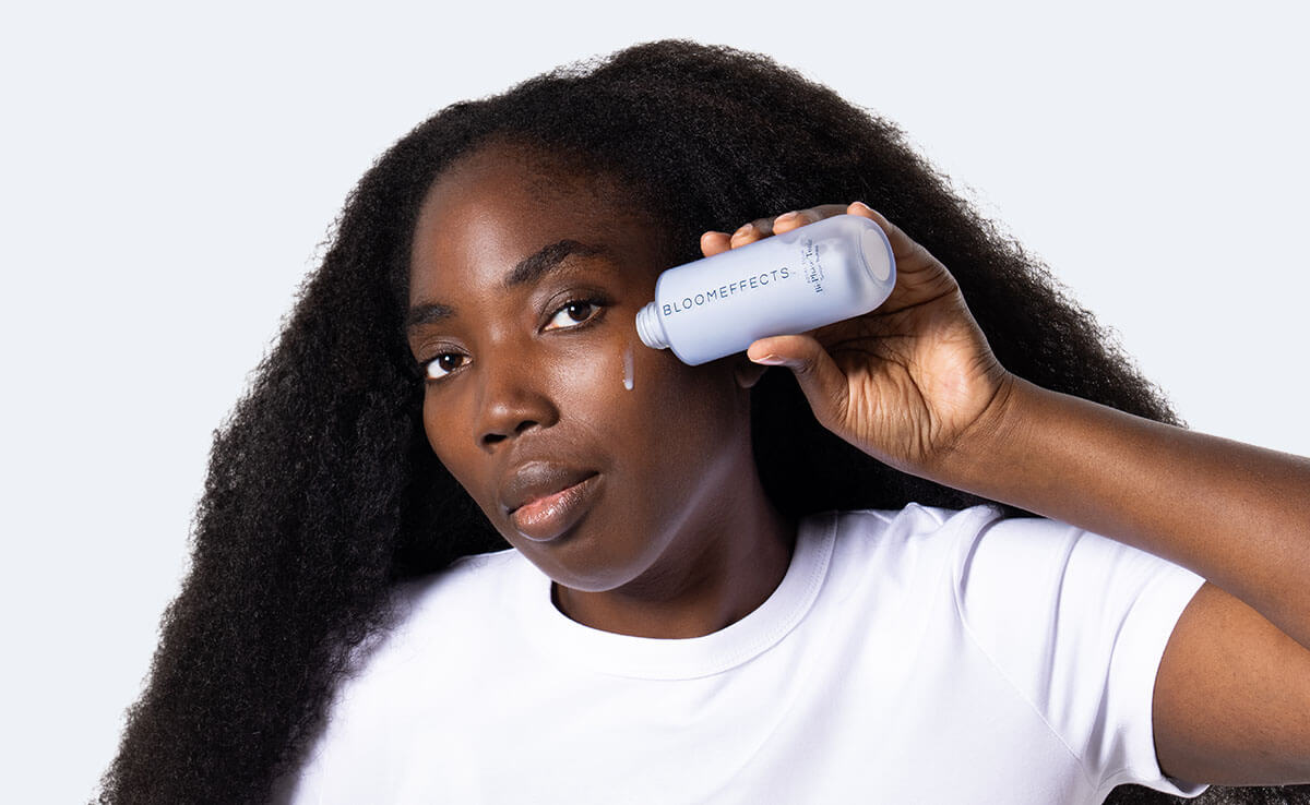 Woman holding Bloomeffects Bi Phase Toner and applying to cheek
