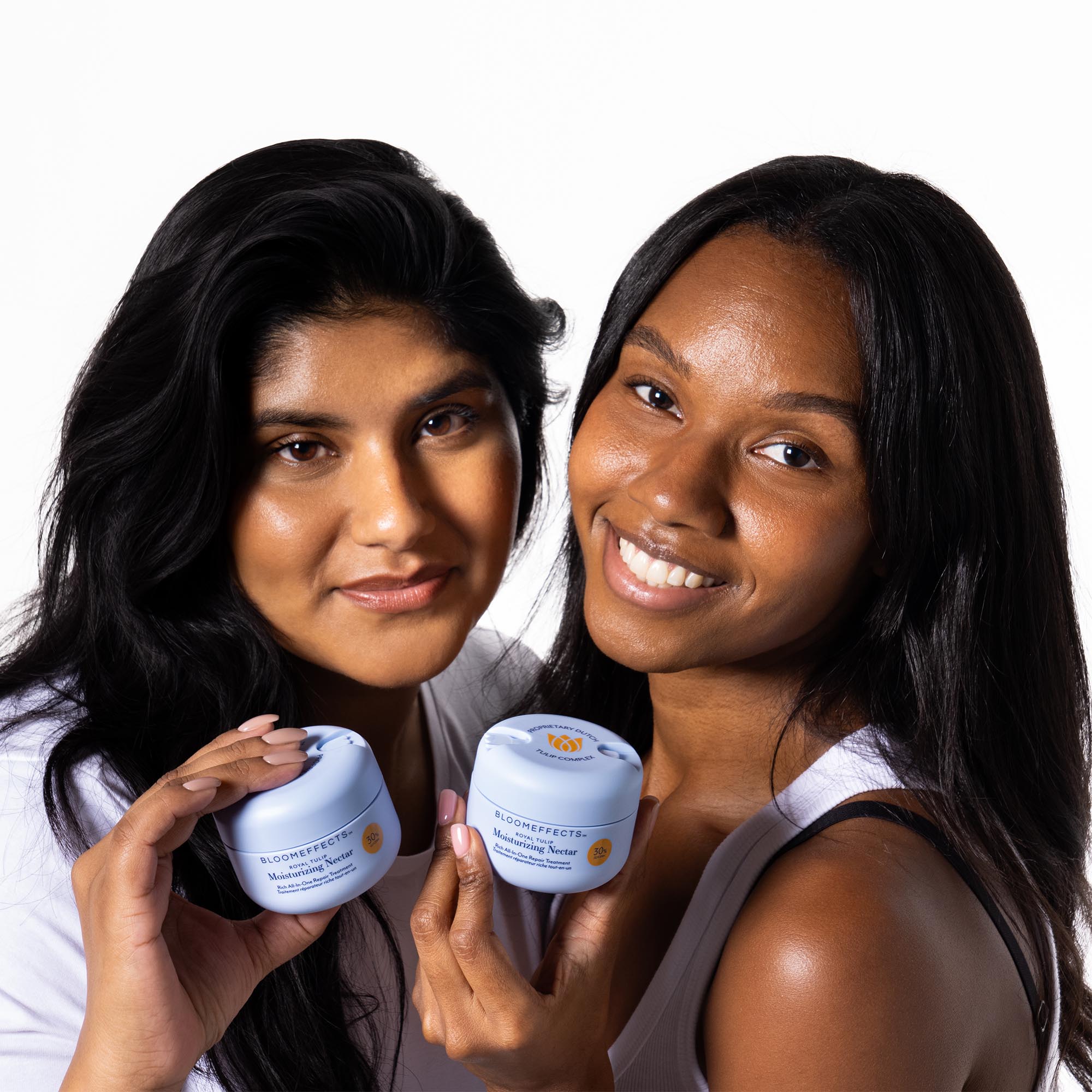 Two women holding and showing Royal Tulip Moisturizing Nectar against a white background